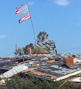 A tattered, windblown American flag stands defiantly amid the aftermath of Hurricane Harvey.