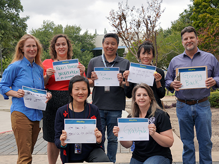 TCEQ volunteers who deliver meals on Fridays hold up signs stating why they volunteer. Left to right—back row: Patricia Wise, Jessica Uramkin, Ivan Wong, Maithi Nguyen, and Jeff McEntire; front row: Mary McKelvy and Gayle Stewart.
