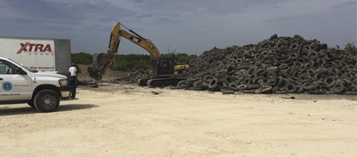 An excavator loads scrap tires into a waiting truck as part of the multi-agency cleanup effort at the Gatesville scrap tire site where 268,000 scrap tires once littered the landscape.