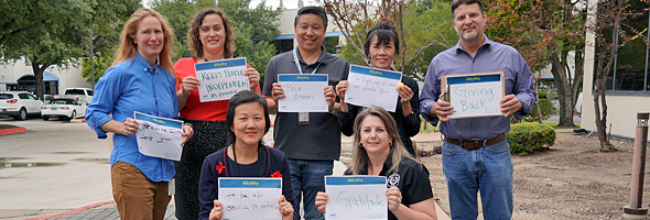 TCEQ employees hold signs explaining why they volunteer for Meals on Wheels