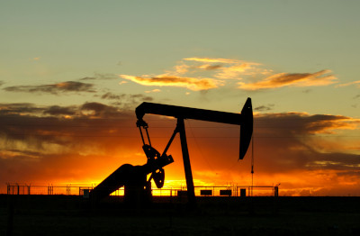 Silhouette of pumpjack against vibrant orange and yellow sunset