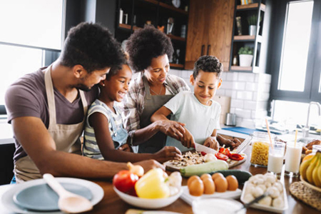 A family of four working together in the kitchen